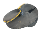 Close-up of a black circular platform with a curved row of yellow-tipped pegs along a chain-like track attached to it.