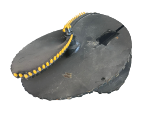 Close-up of a black circular platform with a curved row of yellow-tipped pegs along a chain-like track attached to it.