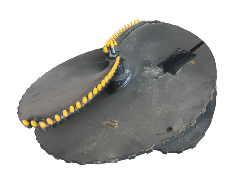 Close-up of a black circular platform with a curved row of yellow-tipped pegs along a chain-like track attached to it.