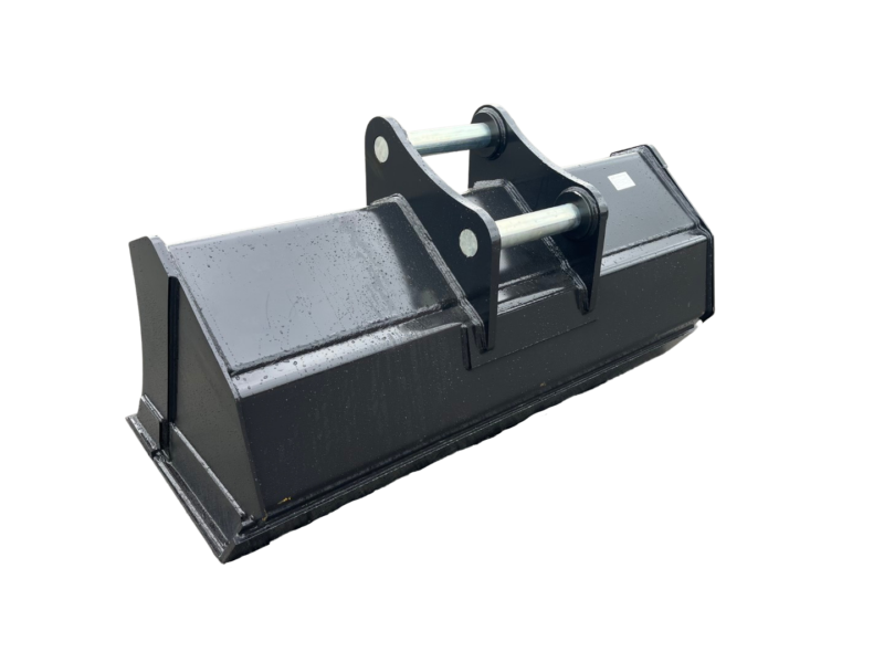Large steel excavator bucket attachment with mounting pins, resting on a concrete surface in an industrial yard.
