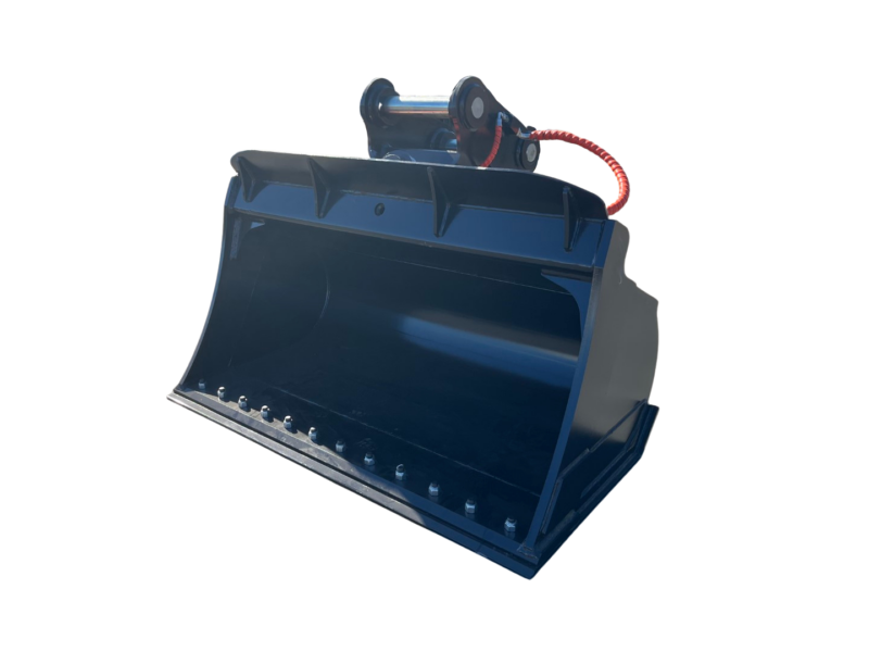 Blue steel excavator bucket attachment with bolt-edged lip sits on a paved lot; red hydraulic hose nearby in a yard.