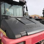 Front view of a red Dynapac road roller with a black hood and cab, parked on a construction site.