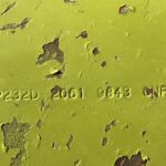 Close-up of lime-yellow, chipped metal surface with stamped codes: P232D 2061 9843 CNF.