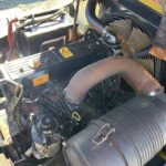 Open engine bay of a vehicle showing the inline engine, large intake hoses, and labeled oil components like 'Engine Oil' near the valve cover area.