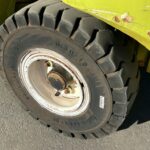 Close-up of a large rugged tire on a yellow industrial vehicle, showing worn treads and rusty wheel hub.